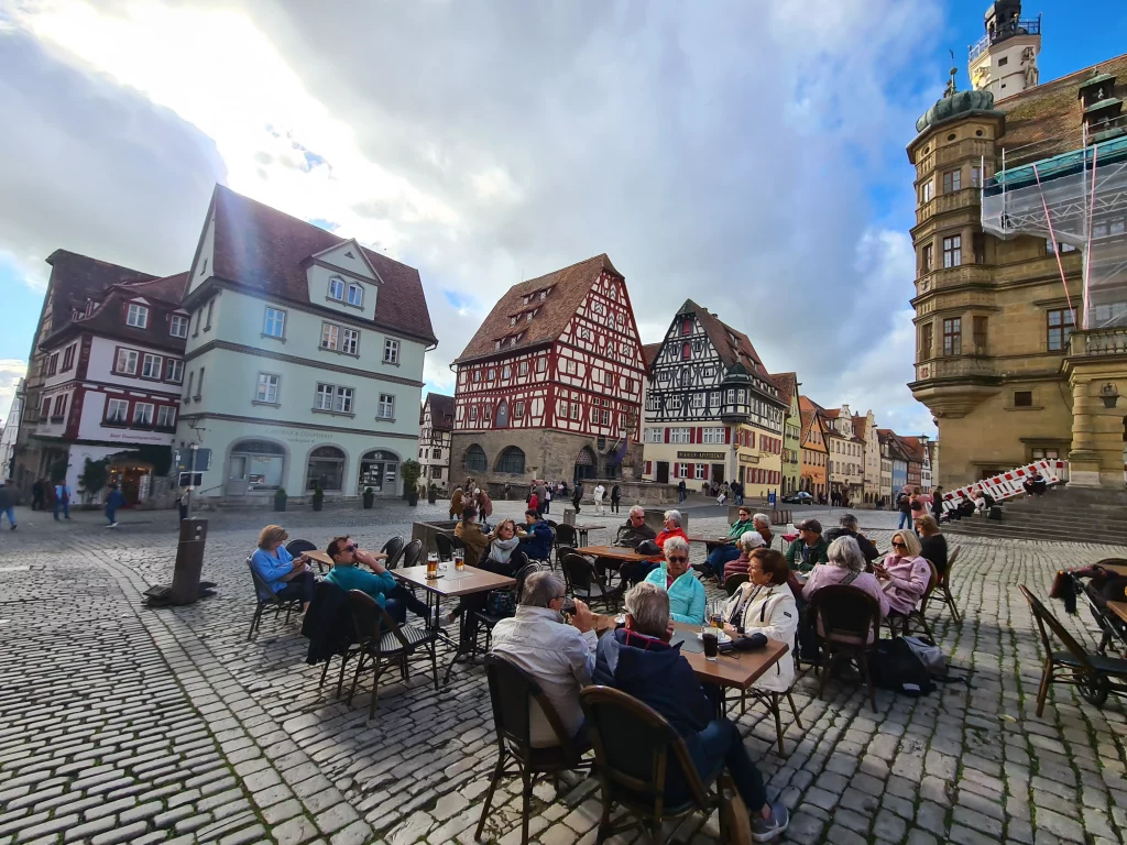 Old city Rotenburg with a pedestrian area, with people sitting at tables surrounded by medieval wood frame houses