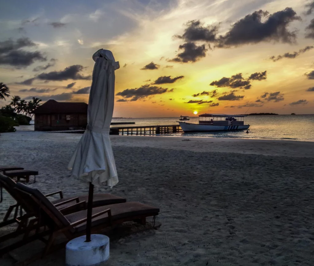 Sunset on a beach in Maldives, with a boat in the background
