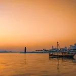 Sunset shot of Doha new city from the old town side, a traditional fishing boat in the foreplan with the skyscrapers in the far background.