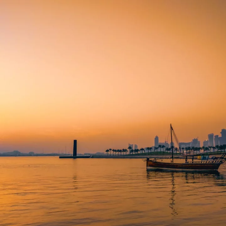 Sunset shot of Doha new city from the old town side, a traditional fishing boat in the foreplan with the skyscrapers in the far background.