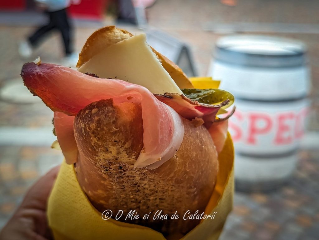 A ready done sandwich in a baguette with meat, cheese, and pickles.