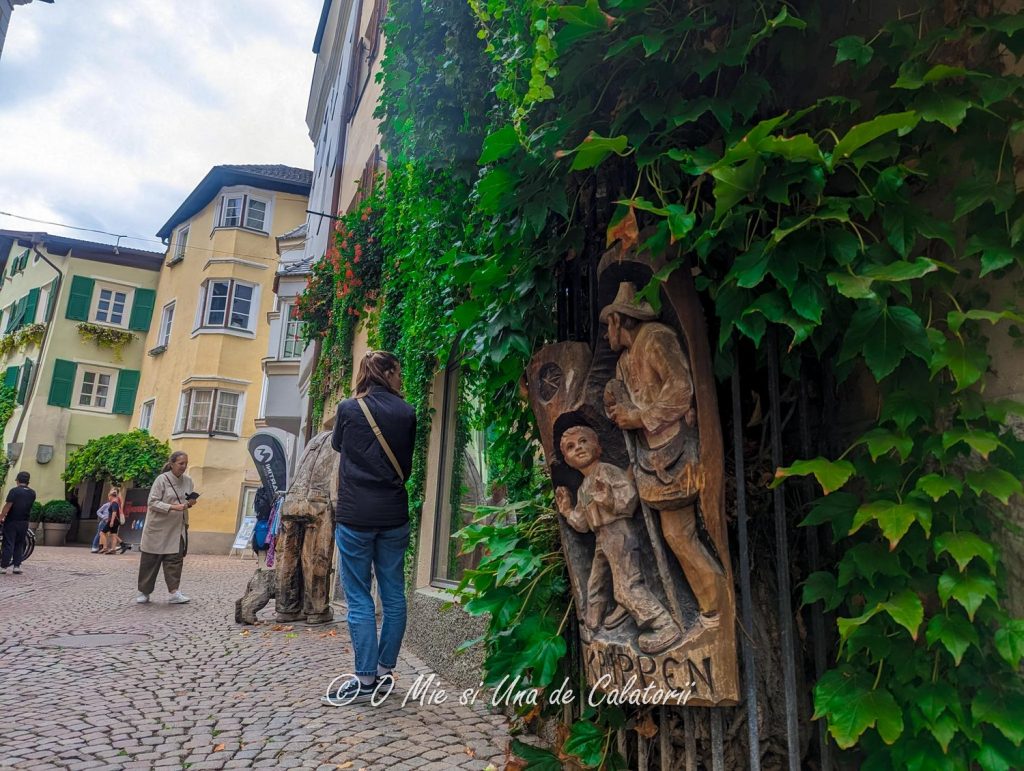a wood sculpture on the side of a house, depicting a boy and a adult person with a walking stick