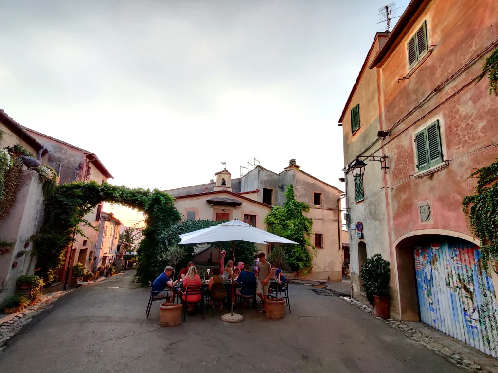 A family having a meal out on the street, between old typical houses, late afternoon
