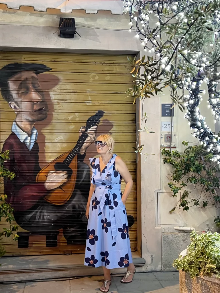 a person siting for a photograph in front of a door that has a painting of a man playing the guitar