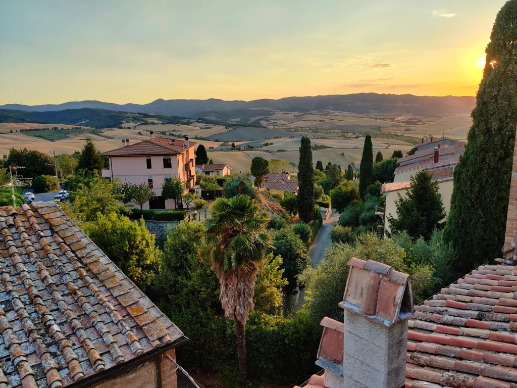 a rage view of the city at sunset, with typical houses and the Tuscan hills/fields in the background