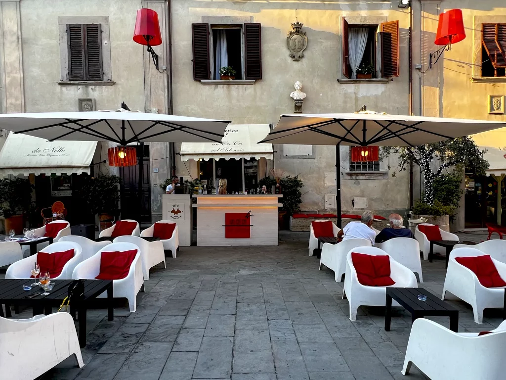 the front of a restaurant with white chairs and small tables