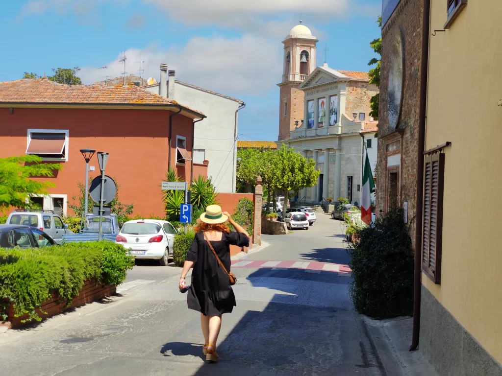 a person walking down a street with coloured houses around and a church in the far plan