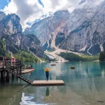 A wide shot of the Lago di Braies, with beautiful blue waters and massive mountains in the bacground