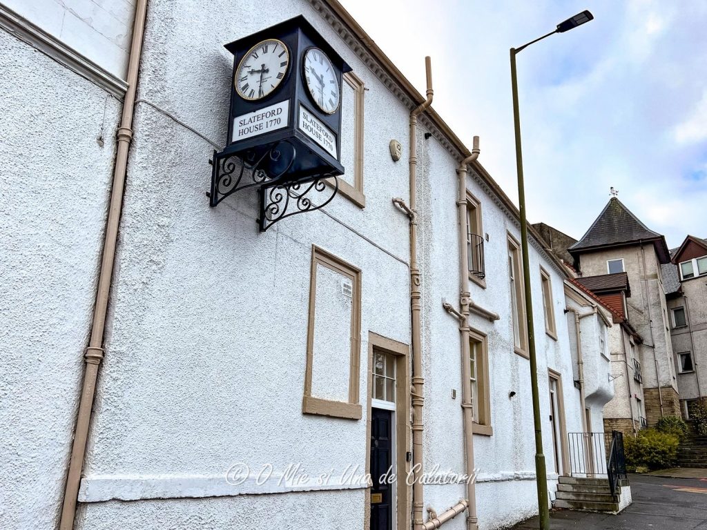 Side street view of the house, with a clock on a metallic frame