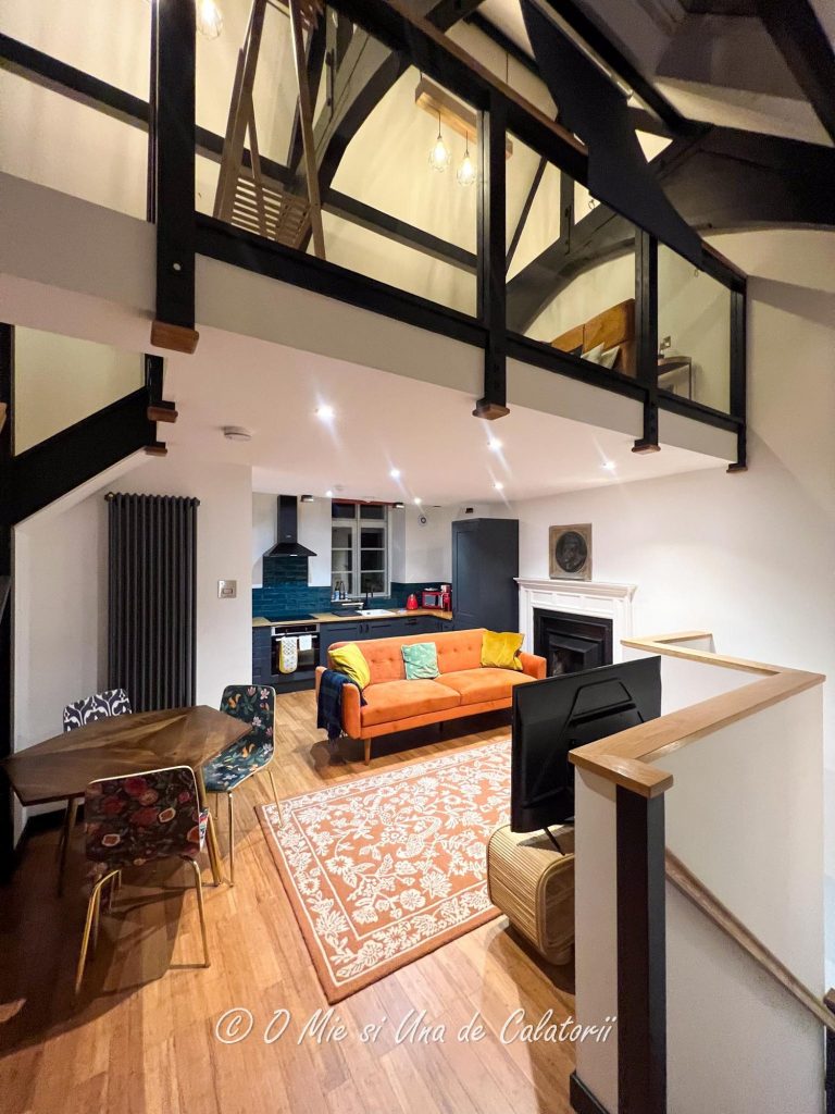 Main room view, with a sog=fa in the middle of the room, and an open space kitchen
