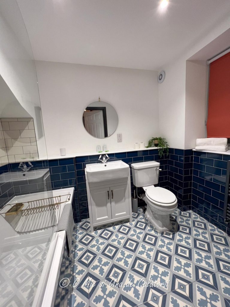 A view of the first bathroom, with a shower, sink, nice flooring.