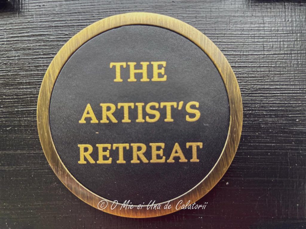 A cup holder with the room branding "The Artist