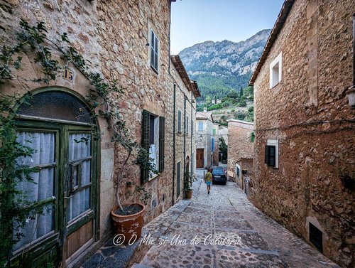 a small cobble street, with old houses on sides, hills in the far view