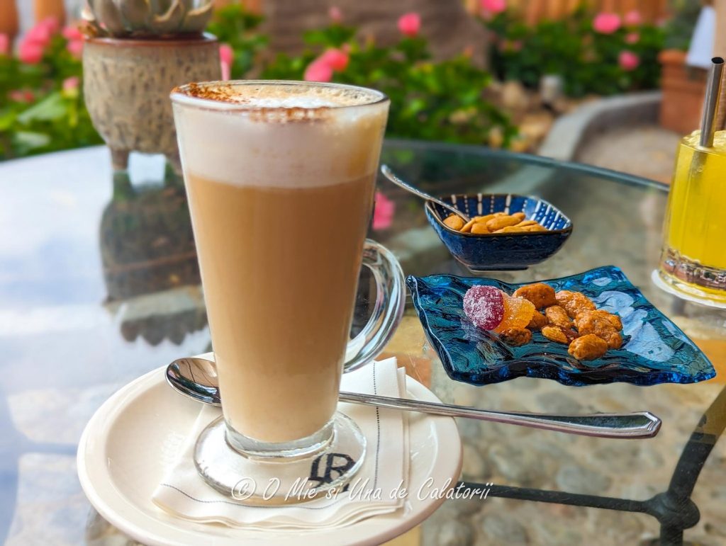 a closeup shot of a latte cup with some sweets served at the terrace