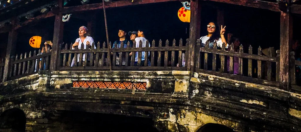 A close up shot of a old bridge with tourists traversing and posing for photographs