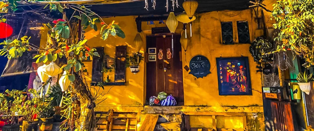 the façade of a yellow house in the Vietnamese style, with many plants and paper Lanterns.