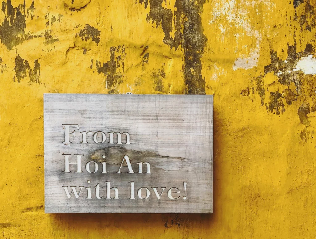 A decorative plaque with the writing From Hoi An with Love! on a yellow wall