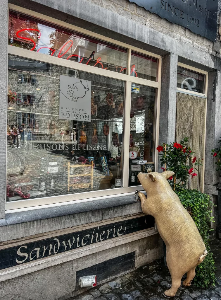 Belgium Durbuy the front of a butchery with a pig (statue) looking inside the window
